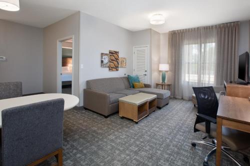 a living room with a couch and a room with a table at Staybridge Suites Auburn Hills by IHG in Auburn Hills