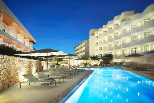 a swimming pool with chairs and umbrellas next to a building at Inturotel Cala Esmeralda Beach Hotel & Spa - Adults Only in Cala d´Or