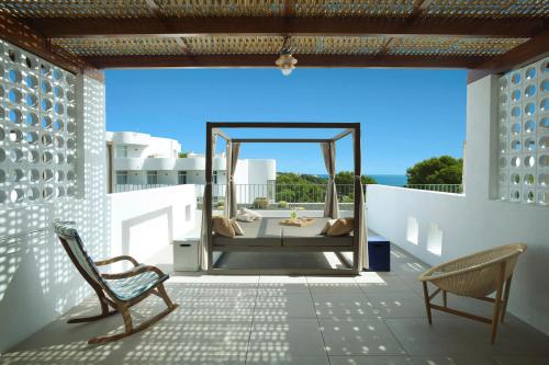 a patio with two chairs and a bed on a balcony at Inturotel Cala Esmeralda Beach Hotel & Spa - Adults Only in Cala d´Or