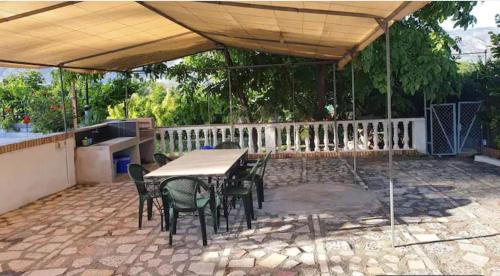 eine Terrasse mit einem Tisch und Stühlen unter einem Baldachin in der Unterkunft Casa rural en Padul entre Sierra Nevada y la Costa in Granada
