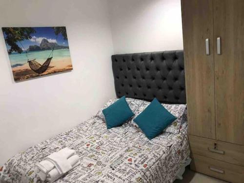 a bedroom with a bed with blue pillows at Hotel Orduz Centro Histórico de Cali in Cali