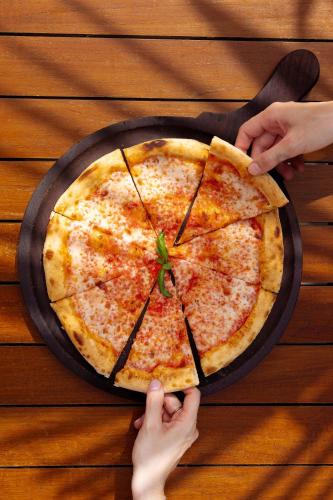 a person holding a pizza on top of a table at Baglioni Resort Maldives - Luxury All Inclusive in Dhaalu Atoll