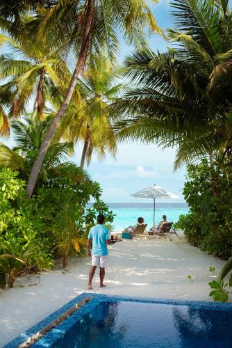 a man standing next to a swimming pool on a beach at Baglioni Resort Maldives - Luxury All Inclusive in Dhaalu Atoll