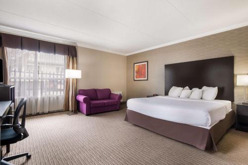 a hotel room with a large bed and a purple chair at Best Western Little River Inn in Simcoe