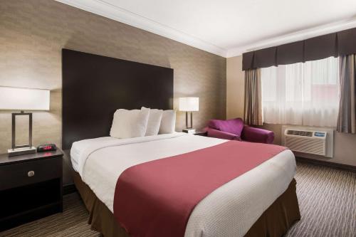 a hotel room with a large bed and a purple chair at Best Western Little River Inn in Simcoe