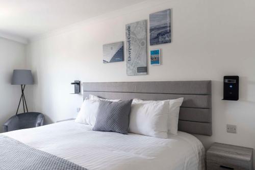 a bedroom with a bed with white sheets and pictures on the wall at The Bolton Stadium Hotel, a member of Radisson Individuals in Bolton