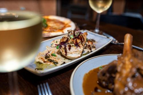 a table with two plates of food and a glass of wine at The Bolton Stadium Hotel, a member of Radisson Individuals in Bolton