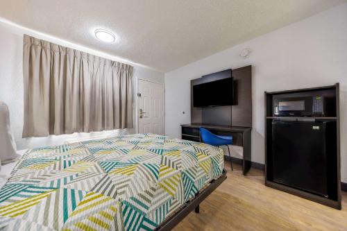a bedroom with a bed and a flat screen tv at Motel 6 Fort Worth, TX East in Fort Worth