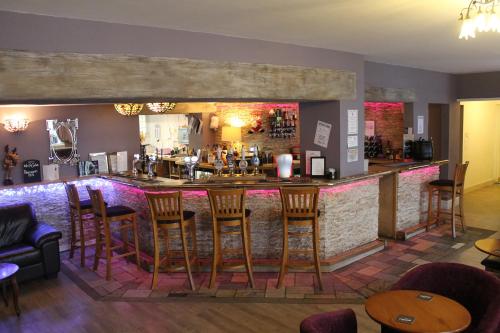 - un bar avec des tabourets en bois dans un restaurant dans l'établissement Swan Motel, à Beccles