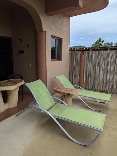 two green lounge chairs and a table on a porch at Casa Arcoiris Zihuatanejo B&B in Zihuatanejo