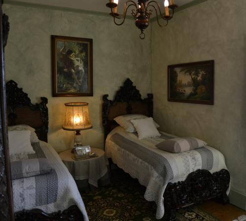 a bedroom with two beds and a table with a lamp at Château de Peufeilhoux in Vallon-en-Sully