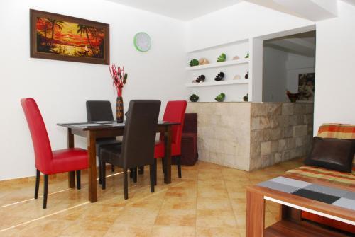 een eetkamer met een tafel en rode stoelen bij Apartments Jovan in Tivat