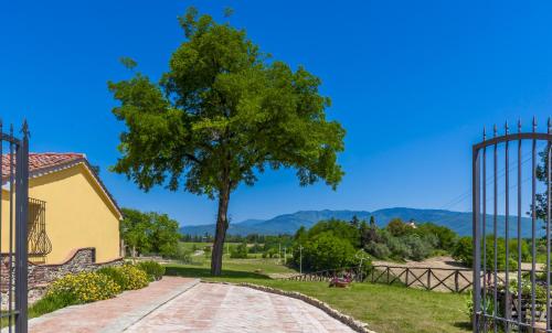 a tree next to a building with a gate at Casa Vacanze Le Fornaci in Laterina