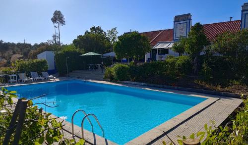 a swimming pool with a wooden deck next to a house at Casa do Campo com Piscina no Alentejo in Quinta de Sancha Cabeça