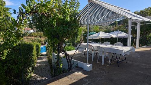 a white table and chairs under a canopy next to a pool at Casa do Campo com Piscina no Alentejo in Quinta de Sancha Cabeça