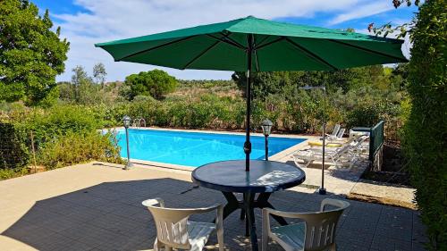 a table with a green umbrella next to a pool at Casa do Campo com Piscina no Alentejo in Quinta de Sancha Cabeça