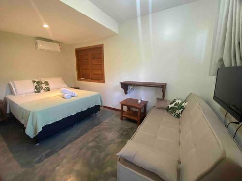 a hotel room with a bed and a couch at Flat com piscina e perto do mar Taipus in Marau