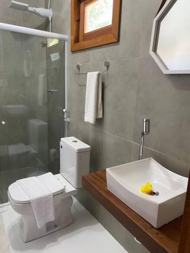 a bathroom with a toilet and a sink and a shower at Flat com piscina e perto do mar Taipus in Marau