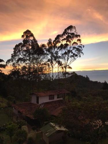 a house on a hill with a sunset in the background at El Barranquero in Cali
