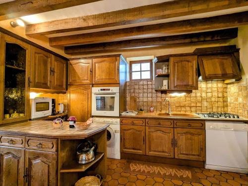 - une cuisine avec des placards en bois et des appareils blancs dans l'établissement Gîte chaleureux au cœur du Berry, proche Château de Valençay et Zoo de Beauval, jardin clos et calme - FR-1-591-33, à Gehée