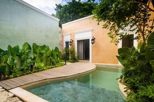 a swimming pool with a wooden walkway next to a building at Casa Clementina Luxe Rustic Haven 5 star Location in Mérida