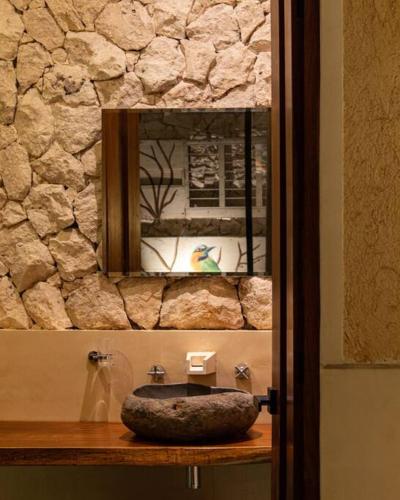a bathroom with a stone sink and a mirror at Casa Clementina Luxe Rustic Haven 5 star Location in Mérida