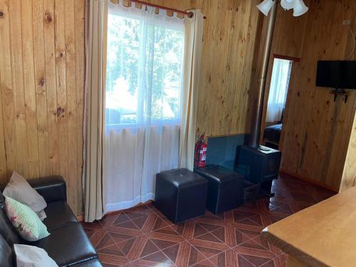 a living room with a couch and a large window at Cabañas Mawidantu Lemu in Las Trancas