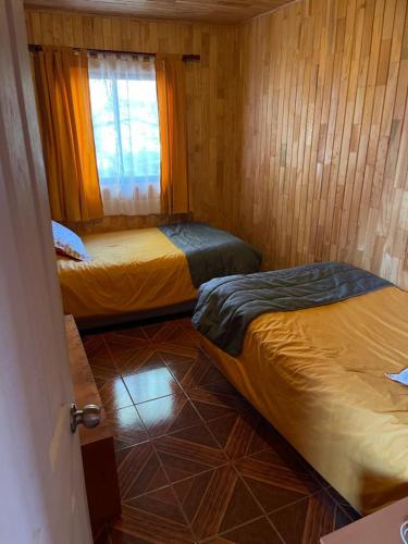 a room with two beds and a window at Cabañas Mawidantu Lemu in Las Trancas
