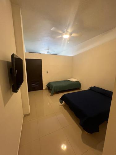 a small room with two beds and a tv at Suites Mar de Cortes in Mazatlán