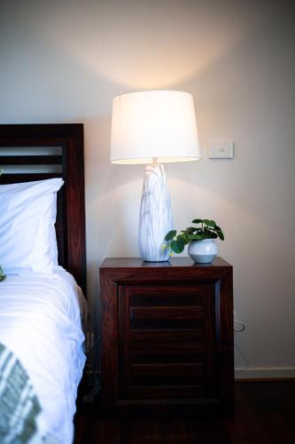 a lamp on a night stand next to a bed at StayAU 5BR Idyllic Lakefront Escape Point Cook in Point Cook