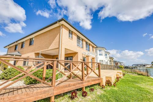 a house with a wooden deck in front of it at StayAU 5BR Idyllic Lakefront Escape Point Cook in Point Cook