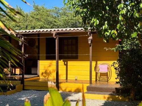 a yellow house with a chair on a porch at Jan Kok Lodges in Willibrordus