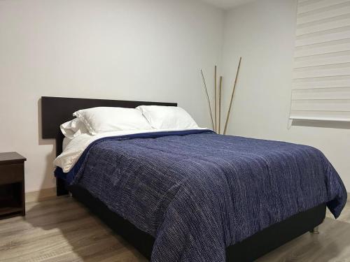 a bedroom with a bed with a blue blanket on it at Apartamento frente a Mallplaza in Manizales