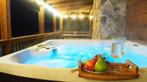a hot tub with a bowl of fruit and glasses of wine at Wears Valley Cabin on 5 Acres, Hot Tub, Pets in Sevierville