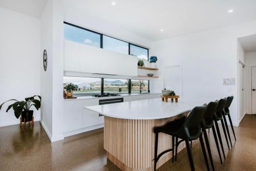 a kitchen with a large white island with black chairs at Mudgee Haven - Stunning Terra Modern Design in Mudgee