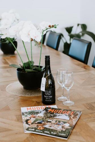 a bottle of wine and two glasses on a table at Mudgee Haven - Stunning Terra Modern Design in Mudgee