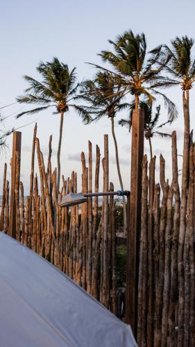 a wooden fence with palm trees in the background at Chalé Vista Mar Tatajuba in Tatajuba