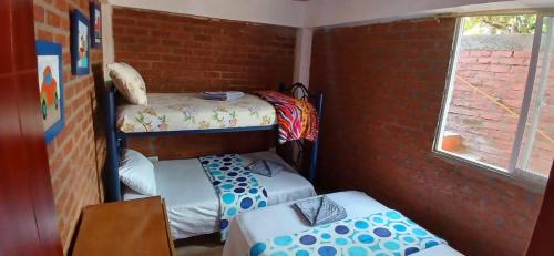 a room with two bunk beds and a brick wall at Entre Aves hospedaje in Luna Park