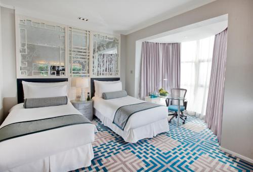a hotel room with two beds and a desk at Dorsett Shanghai in Shanghai