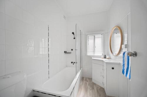 a white bathroom with a shower and a sink at Summer Breeze Forster in Forster
