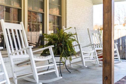 a row of white chairs on a porch with a plant at Elegant Gem*Spacious 5BR*King beds*near Duke in Durham