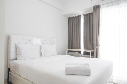 a white bedroom with a white bed and a window at Modern Look Studio Room at Citra Living Apartment By Travelio in Jakarta