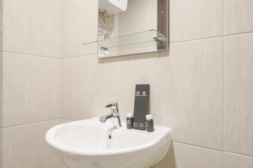 a white bathroom with a sink and a mirror at Modern Look Studio Room at Citra Living Apartment By Travelio in Jakarta