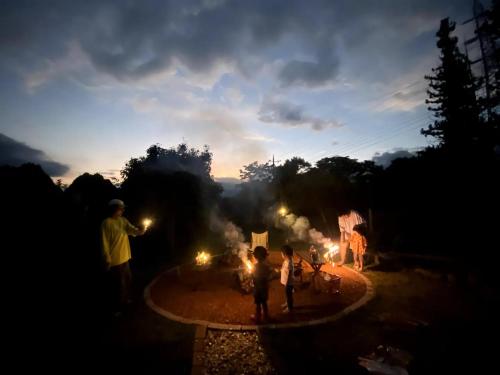 a group of people standing around a fire at night at 一棟貸し別荘 mitt house inn in Numata