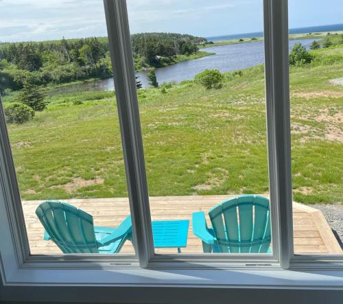 two blue chairs sitting on a deck looking out a window at Colindale Beach Villas -- MIni Villas in Port Hood