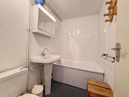une salle de bain blanche avec un lavabo et une baignoire dans l'établissement Appartement cosy · Proche pistes · Balcon · Parking privé - FR-1-344-1199, aux Menuires