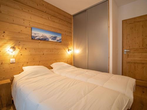 - une chambre avec un lit blanc et un mur en bois dans l'établissement Valmorel: Appt 6 pers, 2 ch, parking, wifi, skis aux pieds - FR-1-356-511, à Valmorel