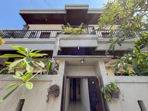 a building with a balcony with plants on it at Adi surya guest house in Seminyak