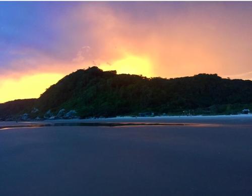 an island in the ocean with a sunset behind it at Loft frente ao mar para 6 pessoas na Ilha do mel in Ilha do Mel