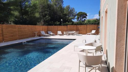 a pool with chairs and tables next to a fence at Logis Hôtel de Port d'Alon - St Cyr sur Mer in Saint-Cyr-sur-Mer